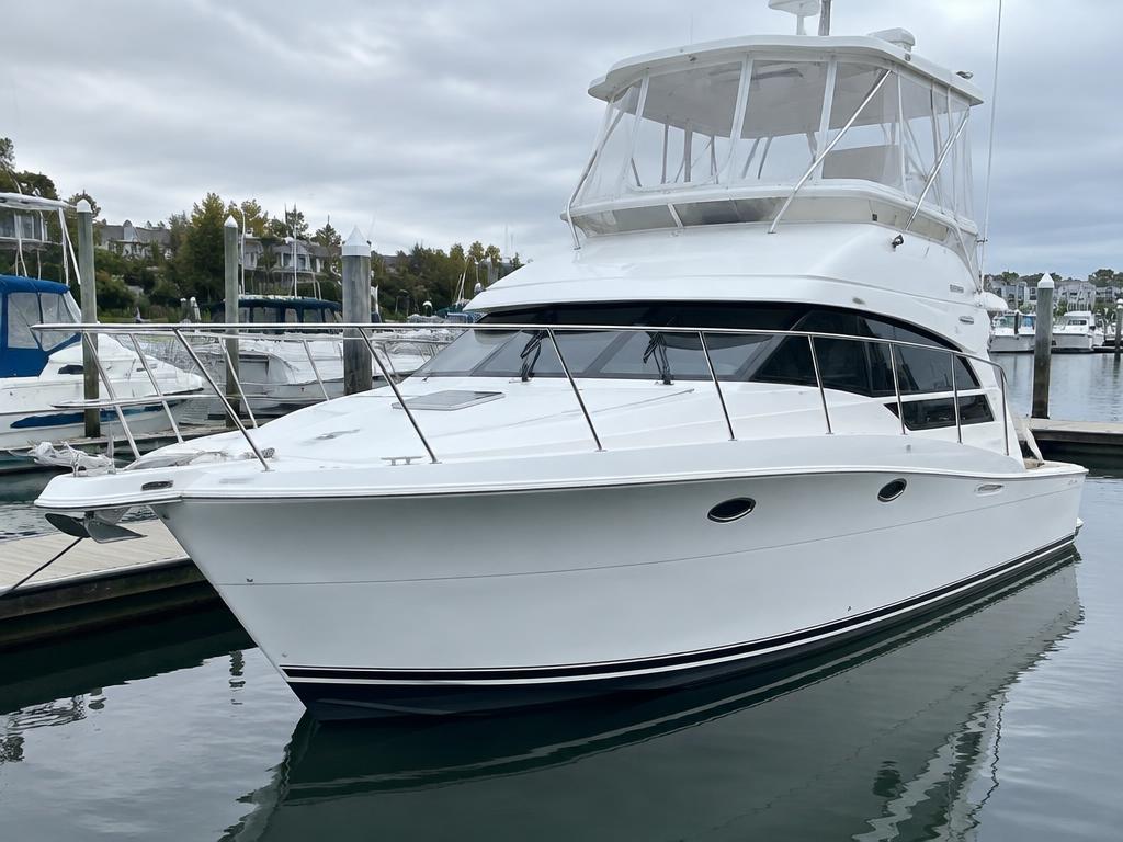 White cabin cruiser with fly bridge docked at a marina